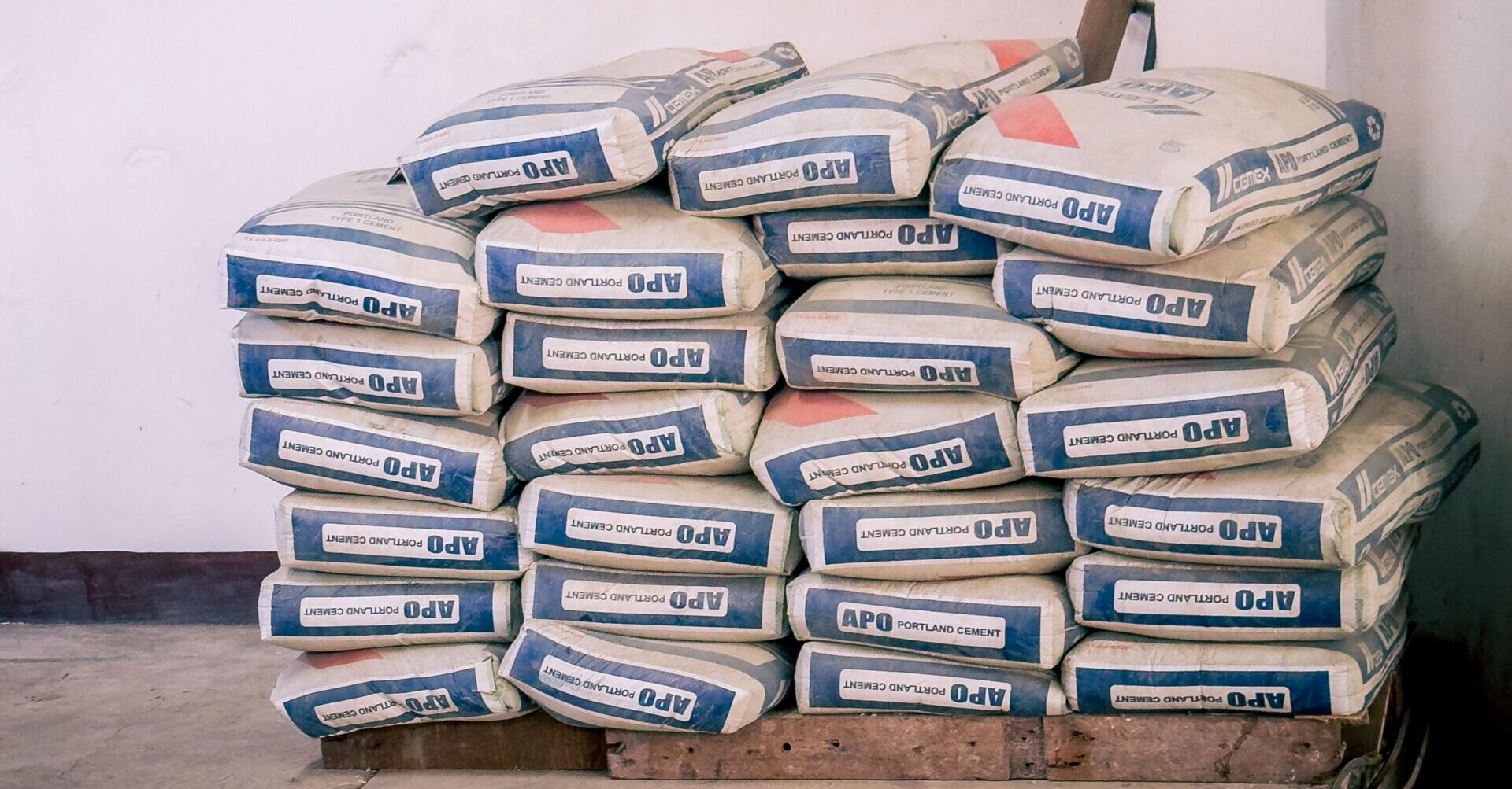 A stack of bags of cement neatly arranged in an indoor warehouse environment.